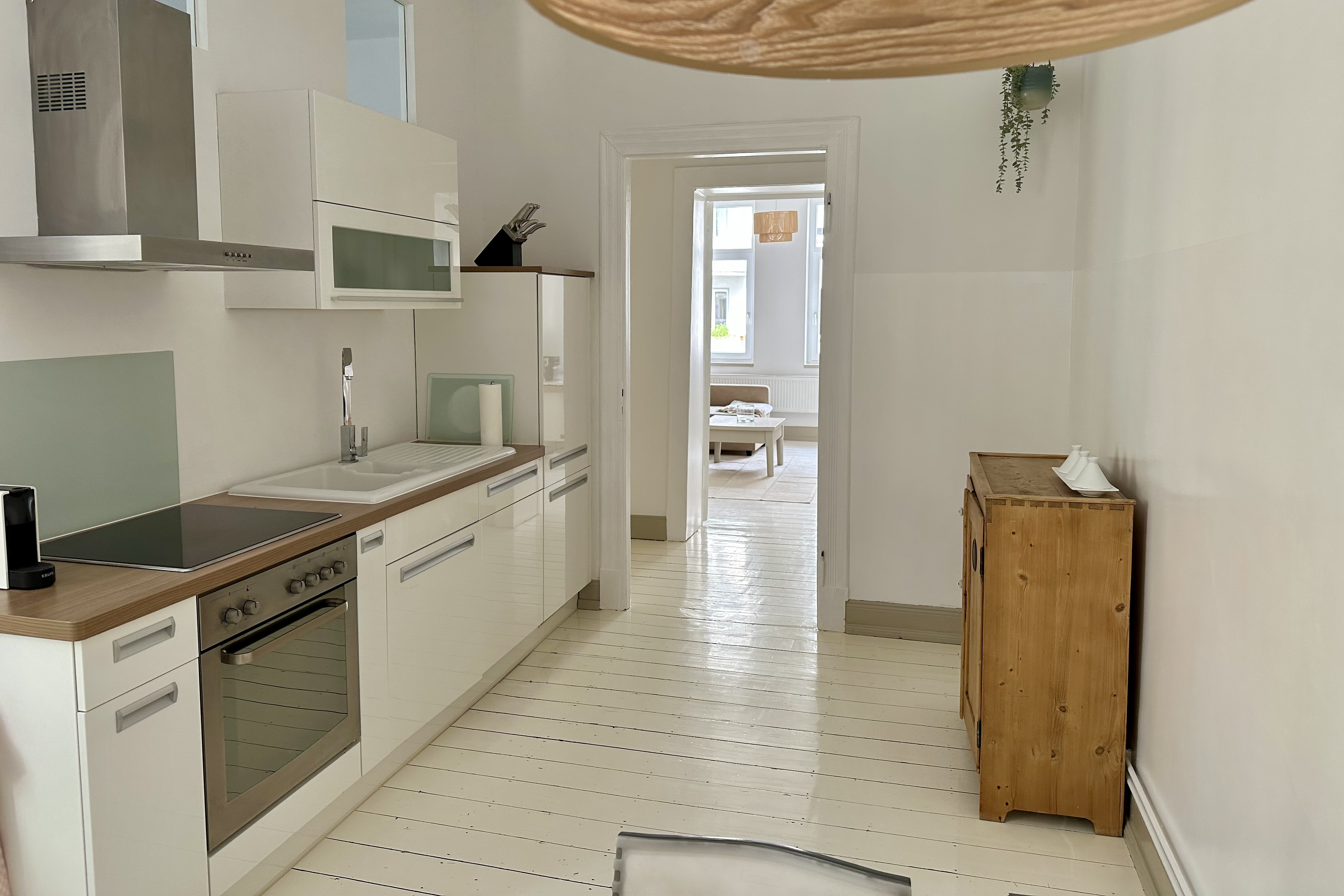 im Vordergrund die weiße Küchenzeile, im Hintergrund der Blick in Richtung Wohnzimmer